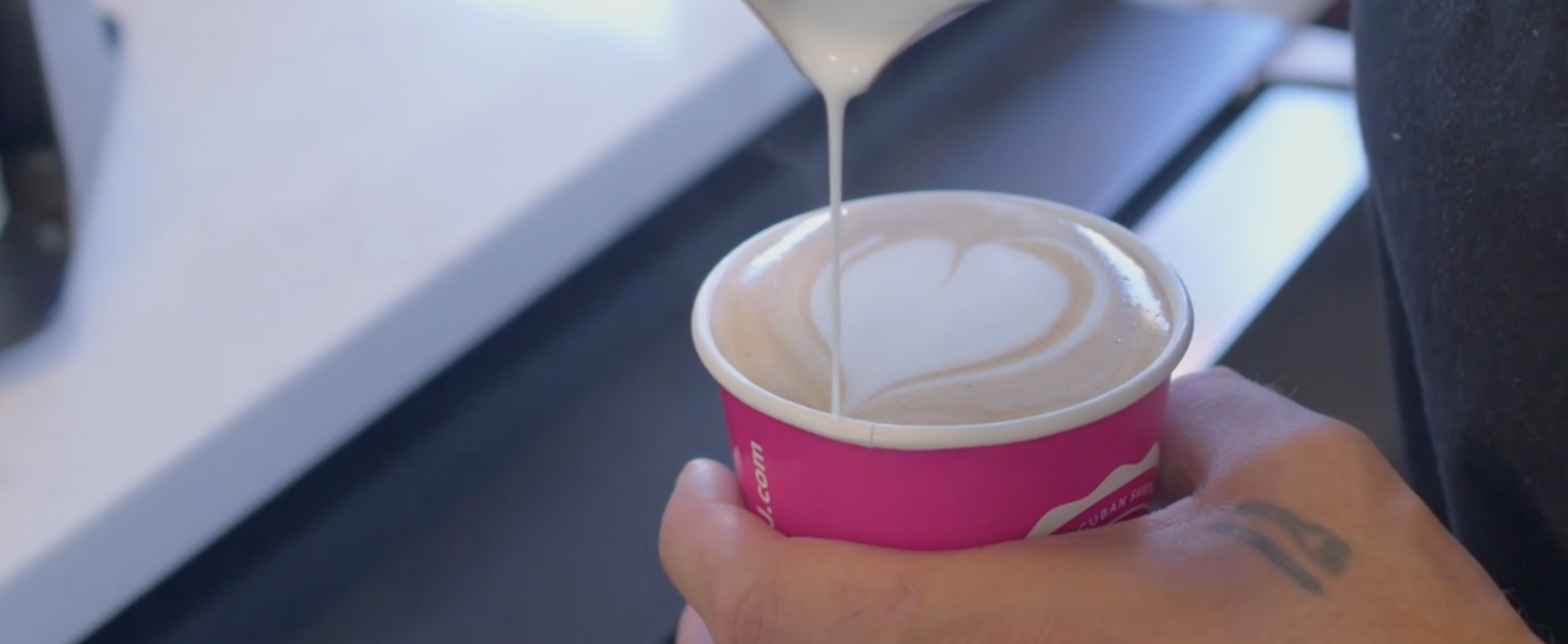 Latte art being poured into a pink Cubita cup