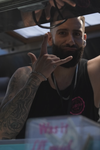 Gus at the food truck window throwing a shaka